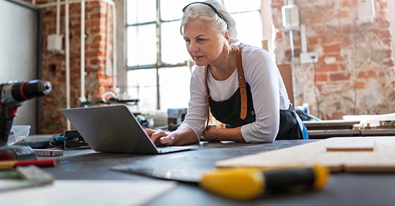 Older Woman on Laptop Researching on Buying vs Leasing Equipment for Her Business