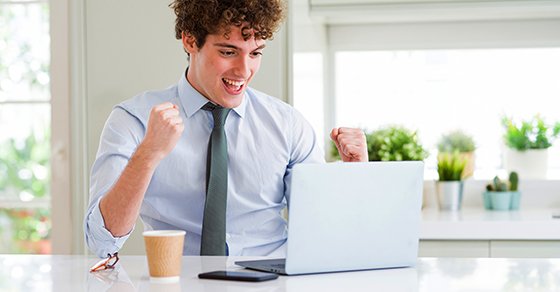 young male showing excitement looking at bis laptop device