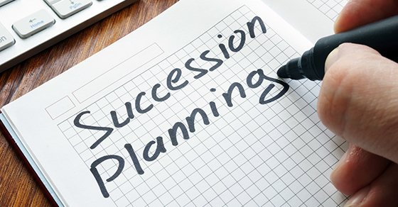 a person writing the text "succession planning" on a notepad with a permanent marker