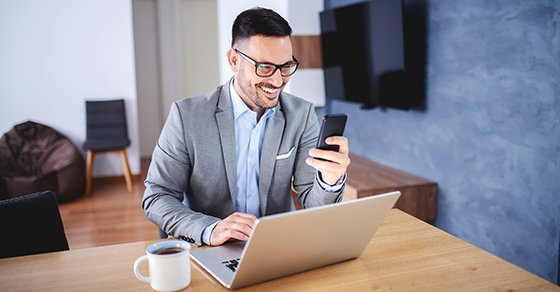 male employee working off of company laptop and holding an iphone