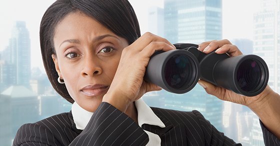 woman in a business suit holding a pair of binoculars